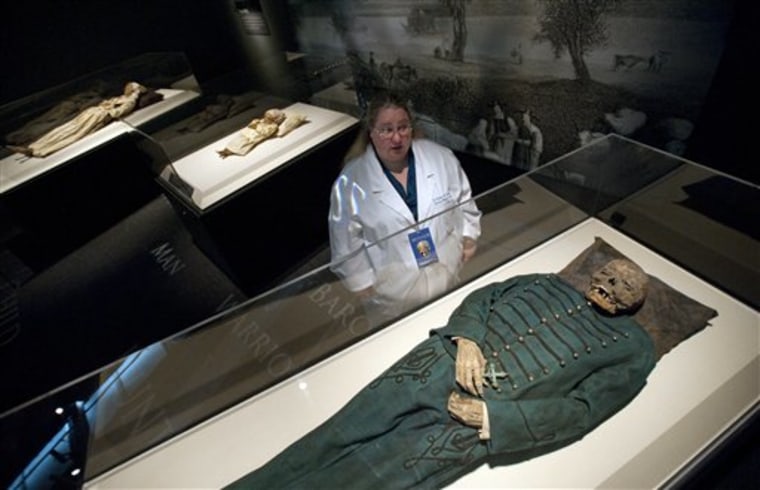 In this June 28, 2010 photo, Dr. Heather Gill-Frerking looks over a family of Hungarian V?c mummies from the 19th Century while preparing to open the new Mummies of the World exhibit at the California Science Center in Los Angeles. The 45 mummies and 95 artifacts in the show come from 15 museums in seven countries, said Marc Corwin, CEO of American Exhibitions Inc. The show opens Thursday at the California Science Center, then will go on a three-year tour across the country. (AP Photo/Adam Lau)